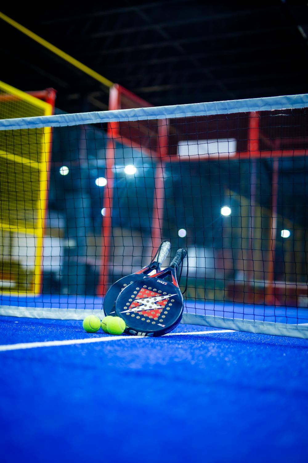 Farverig indendørs padelbane med ketsjer og bolde